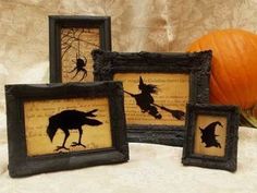 three framed halloween pictures on display next to a pumpkin