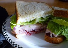 a sandwich on a plate with lettuce and meat in the middle is cut in half