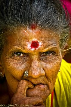 an old woman with a red spot on her forehead and nose is looking at the camera