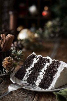 a slice of chocolate cake on a plate next to some cinnamon sticks and pine cones