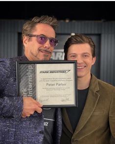 two men standing next to each other holding up an award for their roles in the film