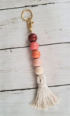 a wooden beaded keychain with tassels hanging from it's side