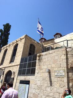 people are standing in front of a building with flags on the roof and one person is taking a photo