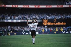 a soccer player is running on the field with his arms in the air as he celebrates