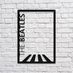 the beatles sign on a white brick wall in front of a black and white frame