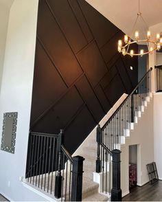 a staircase with black railing and chandelier hanging from it's side wall