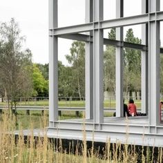 two people are sitting in the window of a building with tall grass and trees behind them