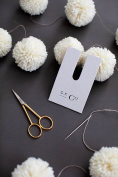 a pair of scissors sitting next to some pom - poms