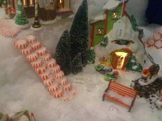 a christmas scene with candy canes and small houses in the snow, trees and lights