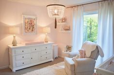 a baby's room with pink walls and white furniture