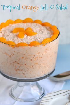 an orange jell oatmeal in a glass dish on a table with silverware