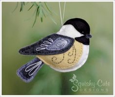 a bird ornament hanging from a branch with the words chickade on it