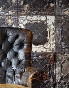 an old leather chair in front of a grungy wall