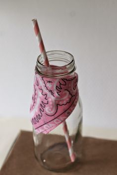 a mason jar with a pink and white straw sticking out of it, sitting on top of a table