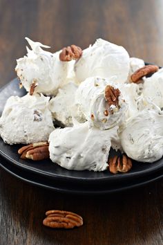 a black plate topped with meringue and pecans on top of a wooden table