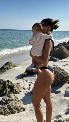 a woman holding a baby on the beach