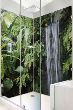 a shower with a waterfall in the middle and green plants on the wall behind it