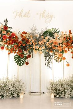 an arrangement of flowers and greenery is displayed on the wall