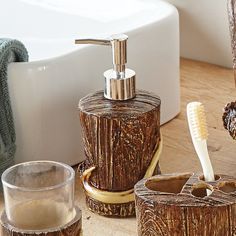 bathroom accessories including soap dispenser, toothbrush holder and glass on wooden table