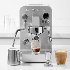 an espresso machine sitting on top of a counter next to a cup of coffee