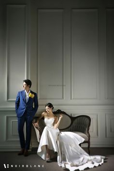 a bride and groom sitting on a couch in front of a wall with white paneling