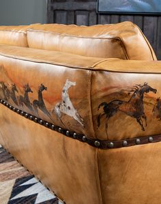 a brown leather couch with horses painted on it's armrests and studded legs