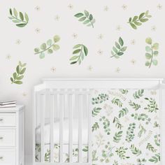 a baby's room with green leaves and flowers on the wall, along with a crib