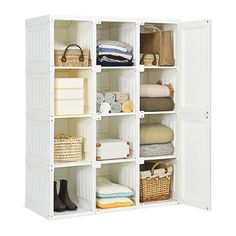 an open white closet with baskets and towels on it's shelves in front of a white wall