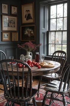 a dining room table and chairs with food on the table in front of it, surrounded by framed pictures