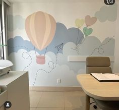 an office with balloons painted on the wall and a desk in front of it,