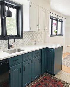 a kitchen with blue cabinets and white counter tops, rug on the floor next to the sink