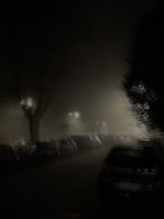 cars parked on the side of a road at night with street lights in the background