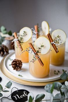 three glasses filled with apple cider sitting on top of a plate