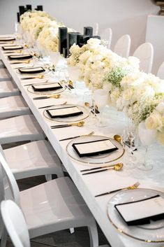 a long table with white flowers and black place settings