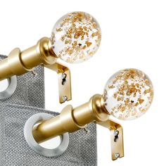 two gold curtain rods with white and gold glitter balls on them