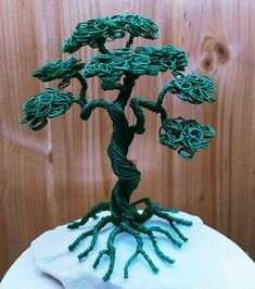 a green wire tree sculpture on top of a white frosted cake covered in icing