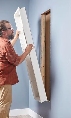 a man is working on an unfinished piece of furniture in the corner of a room