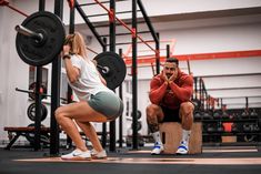 a man and woman squatting in a crossfit gym