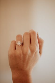 a woman's hand with a diamond ring on her finger, against a white background