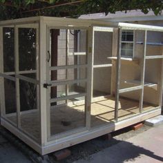 a white chicken coop sitting on the side of a road next to a tree and building