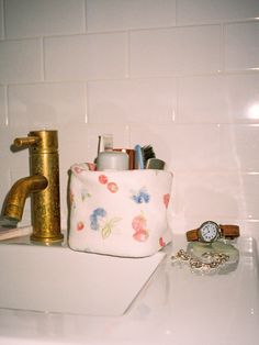 a bathroom sink with toothbrushes, watch and jewelry on it