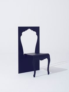 a blue chair sitting in the middle of a room next to a white wall with a shadow on it