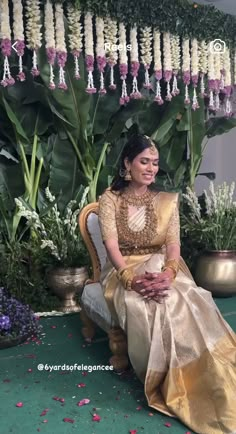 a woman sitting on top of a chair in front of flowers and greenery at a wedding