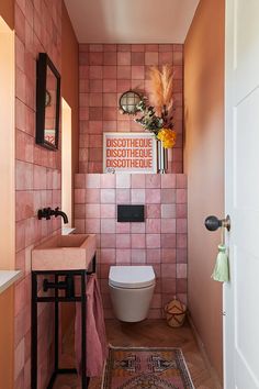 a bathroom with pink tiled walls and wooden floors