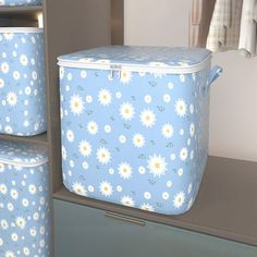 three blue and white storage containers with daisies on them