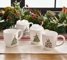 four coffee mugs decorated with christmas trees and candy canes are sitting on a table