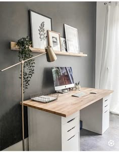 a desk with a computer on top of it next to two pictures and a potted plant