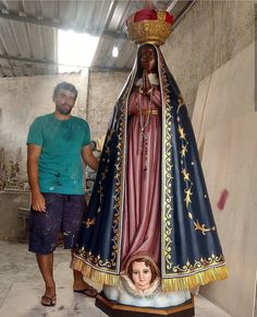 a man standing next to a statue of the virgin mary