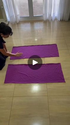 a woman sitting on the floor in front of two purple yoga mats with one person kneeling down