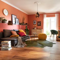 a living room filled with lots of furniture next to a wooden floor covered in books